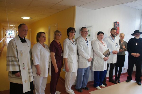 Ligoninės kapeleonas kunigas Tomas Kedušis (iš kairės), skyriaus darbuotojos Miglė Kavaliauskienė, Nijolė Valinskienė, Elena Medvedeva, Gintaras Budrius, Jolanta Navikaitė, Aurimas Žibutis, Asta Teišerskienė ir Virgis Stakėnas šalia neseniai atidengtos atminimo lentos. (Zitos Katkienės nuotr.)